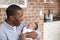 Father At Home Sitting And Holding Newborn Baby Son