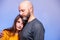 Father hugging his daughter . Man in his 40s, bald with grey beard. girl teenager with long hair. Blue background