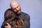 Father hugging his daughter . Man in his 40s, bald with grey beard. girl teenager with long hair. Blue background