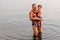 Father hugs his little son while standing in the lake