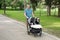 Father with kids in double stroller in a park.  Man pushing twins stroller, pram