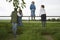 Father With Kids Looking At Lush Landscape By Fence