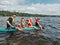 Father with kids swimming on paddle surf board on lake river. Dad with children doing sport summer water activity outdoors.