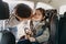 Father kisses his toddler daughter buckled into her baby car seat