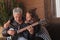 Father learning his teenage daughter to play the electric guitar at home.