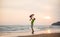 Father lift up daughter on hands on sunset ocean beach with yacht on back