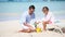 Father and little adorable girl making sand castle at tropical beach