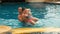 The father with little daughter have fun in the pool. Dad plays with the child. The family enjoy summer vacation in a