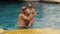 The father with little daughter have fun in the pool. Dad plays with the child. The family enjoy summer vacation in a