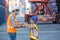 Father and little daughter wearing a safety helmet at Container cargo site. Business heir concept. Happy father and daughter weari