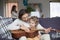 Father and little son with guitar on couch