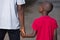 Father and little son holding hands walking on a road