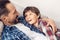 Father and little son at home lying on sofa boy looking at dad excited close-up