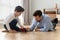 Father and little son playing toy cars on warm floor