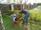 Father and little son work together in a garden with a rake and a wheelbarrow