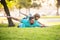Father lying on grass, with excited happy little child son on shoulder. Carefree two man generations family having fun