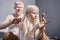 Father is making hairdo to his little loving daughter while sitting at the bed