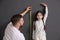 Father measuring daughter`s height near black wall