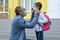 Father in a medical mask puts a protective mask on his daughter on the background of the school.Kid safety after coronavirus