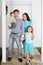 Father, mother, baby and daughter stand on porch of house.