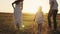 father mother and child run at sunset in sky, silhouette of happy family, little kid sits on dad shoulders, family trip