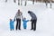 Father, mother and children, twins hold each other hands and walking on the snow