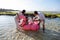 Father and mother holding the children riding a floating flamingo buoy in water