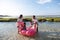 Father and mother holding the children riding a floating flamingo buoy in water