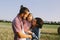 Father and mother hug her little daughter outdoors in field