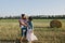 Father and mother hug their little daughter outdoors in field