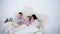 Father, mother and little daughter sneezing with napkins, wearing pajamas and lying in bed.