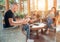 Father, mother, and son family sitting together in Sunroom in cozy armchairs and reading books, using a laptop, and enjoying