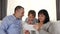 Father, mother and son spend time together sitting on the couch using a tablet. Happy family, technology.