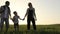 Father, mother and son walking on the field at the sunset time.