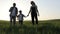 Father, mother and son walking on the field at the sunset time.