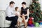 Father and mother talk with daughter on sofa near Christmas tree