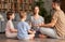Father, mother and two kids sitting in lotus pose on floor and meditating with closed eyes