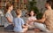 Father, mother and two kids sitting in lotus pose on floor and meditating with closed eyes