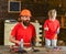 Father, parent with beard in protective helmet teaching little son to use different tools in school workshop. Boy, child