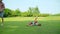 Father playing with daughter in meadow. Woman and boy standing in field