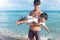 Father playing with kid on tropical sea sand beach together, daddy carrying cute son, joyful parent lifting his boy up on summer