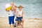 Father playing with siblings on beach in summer