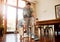 Father pointing to show dust and dirt on wooden floor for son to sweep with broom for household chores at home. Cute boy