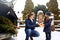 Father presents daughter a gift box on snowy winter day outdoors. Christmas tree in large trunk of family car. Girl