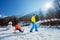 Father pulling uphill a boy on the wooden sledge at mountains