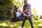 Father Pushing Children On Tire Swing In Garden