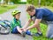 Father putting band-aid on young boy\'s injury who fell off his b