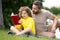 Father read a book with son in a park outdoors. Father and child son reading outdoor on green nature background. Dad