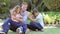 Father Resting In Garden As Daughters Jump On Him