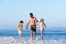 Father Running With Children Along Sandy Beach